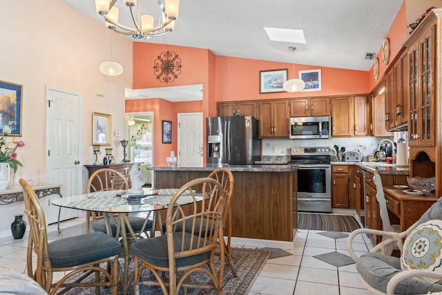 kitchen featuring brown cabinetry, glass insert cabinets, stainless steel appliances, a sink, and light tile patterned flooring