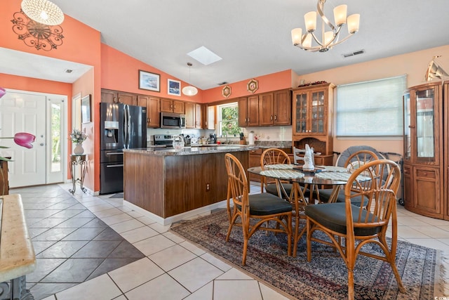 kitchen featuring vaulted ceiling with skylight, visible vents, brown cabinets, stainless steel appliances, and light tile patterned flooring