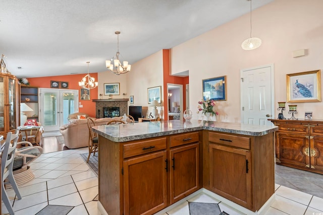 kitchen featuring light tile patterned floors, hanging light fixtures, vaulted ceiling, a fireplace, and a notable chandelier