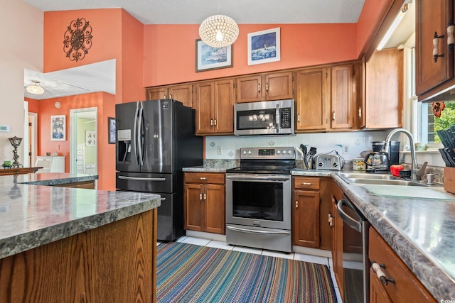 kitchen with light tile patterned floors, brown cabinetry, decorative backsplash, stainless steel appliances, and a sink