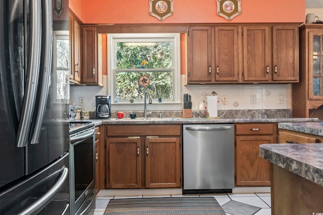 kitchen featuring light tile patterned floors, tasteful backsplash, appliances with stainless steel finishes, and a sink