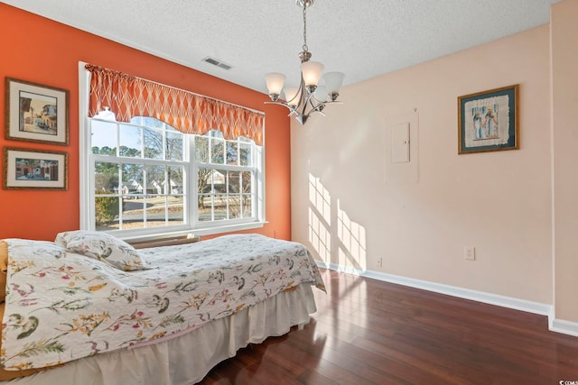 bedroom featuring a textured ceiling, a notable chandelier, dark wood-type flooring, visible vents, and baseboards