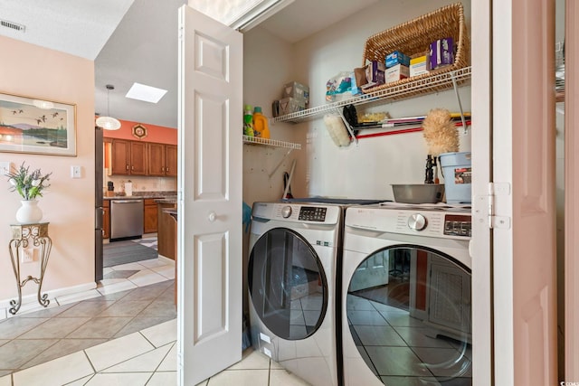 laundry room featuring light tile patterned floors, visible vents, washer and dryer, laundry area, and baseboards