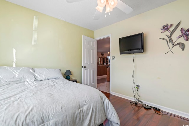 bedroom with a ceiling fan, baseboards, and wood finished floors