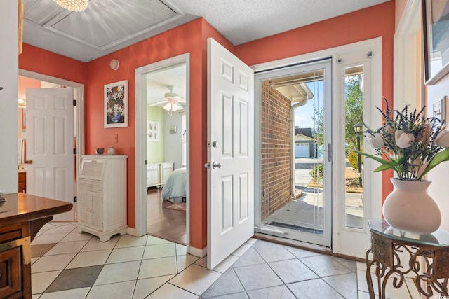 entryway with light tile patterned floors, a textured ceiling, and baseboards