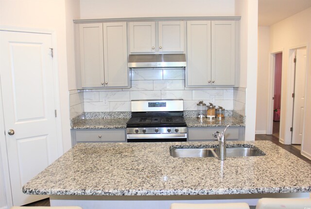 kitchen with sink, backsplash, ventilation hood, light stone countertops, and stainless steel range with gas cooktop