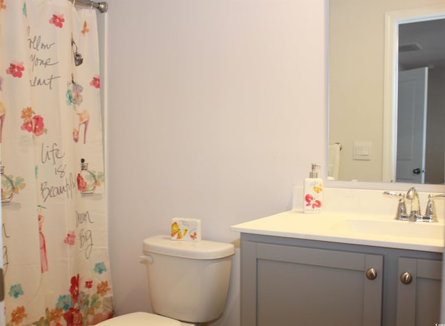 bathroom featuring vanity, walk in shower, and toilet