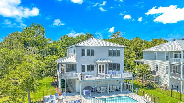 back of house featuring a standing seam roof, a yard, metal roof, and a patio