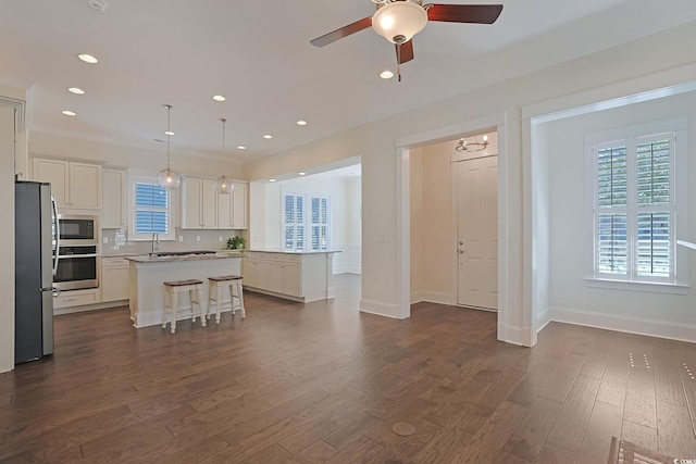 kitchen featuring stainless steel appliances, dark wood-type flooring, backsplash, and a kitchen island