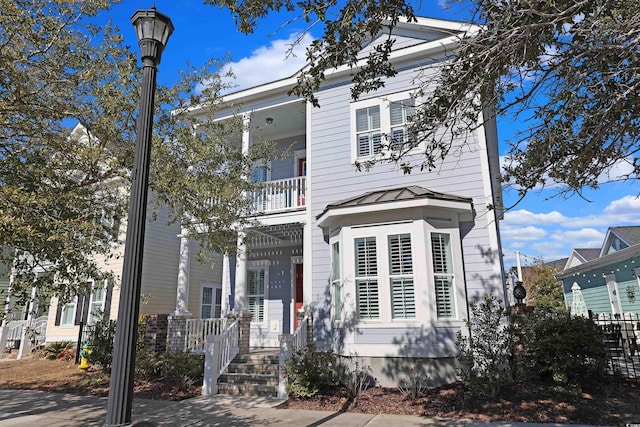 view of front of house featuring covered porch, metal roof, a standing seam roof, and a balcony