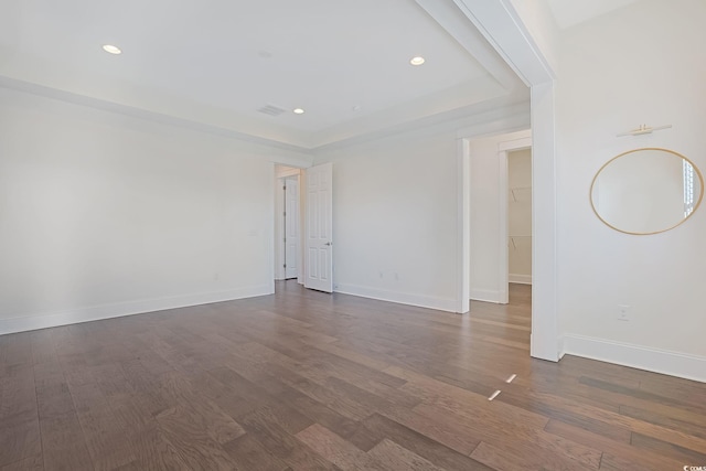 spare room featuring baseboards, a raised ceiling, wood finished floors, and recessed lighting