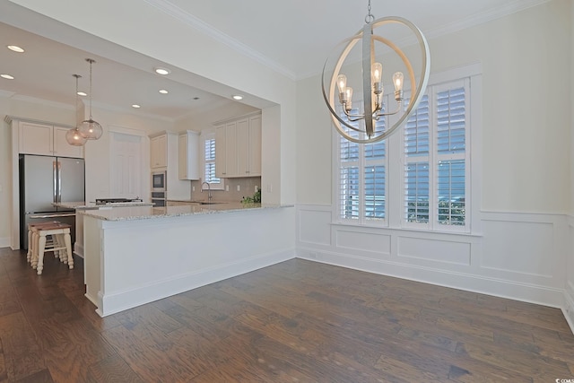 kitchen with appliances with stainless steel finishes, dark wood-style flooring, a chandelier, and light stone countertops