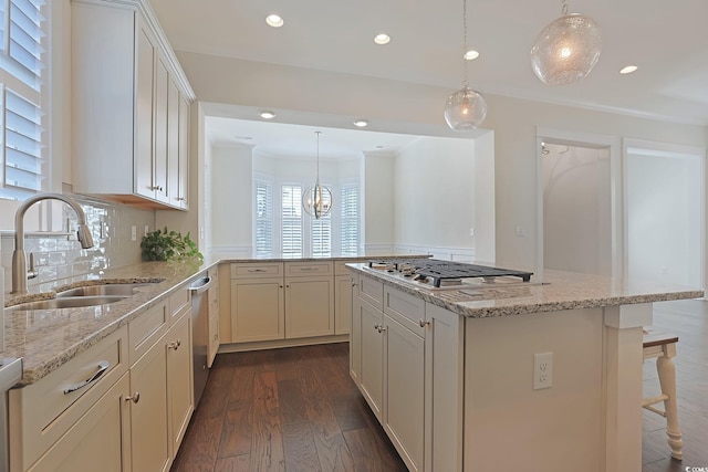 kitchen with dark wood-style floors, light stone counters, appliances with stainless steel finishes, a sink, and backsplash