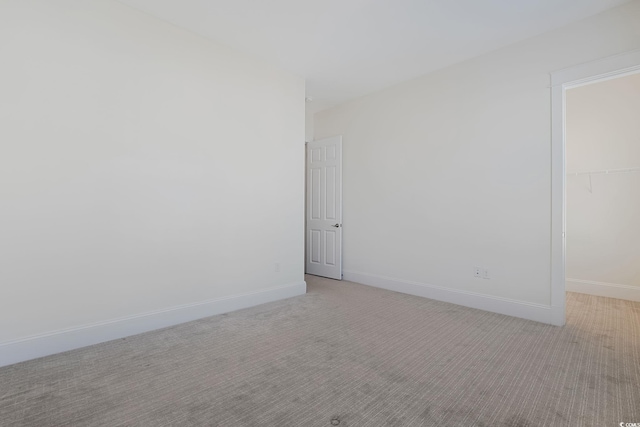 spare room featuring light carpet and baseboards