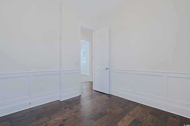 spare room with dark wood finished floors and a decorative wall