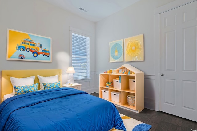 bedroom with visible vents, wood finished floors, and wainscoting