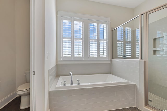 full bathroom with a garden tub, toilet, a stall shower, wood finished floors, and baseboards