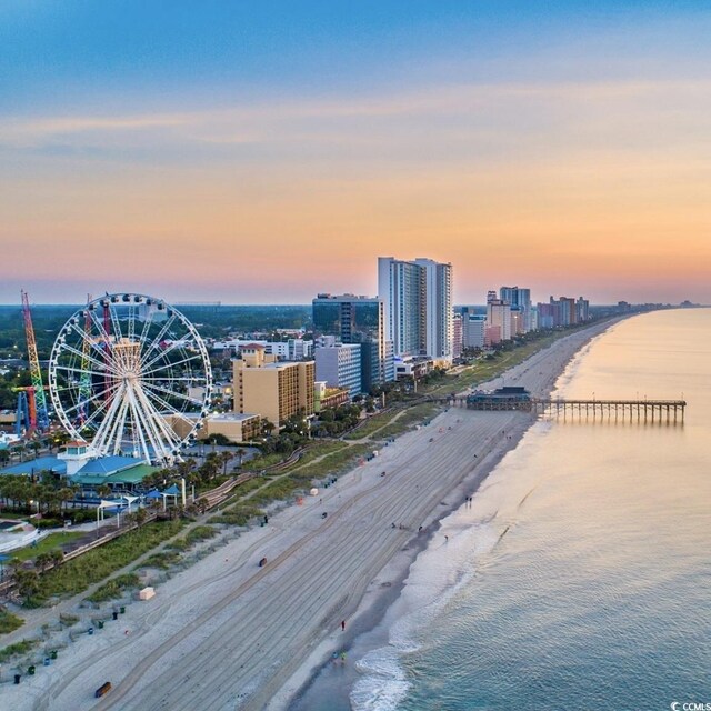 aerial view at dusk with a view of the beach and a water view