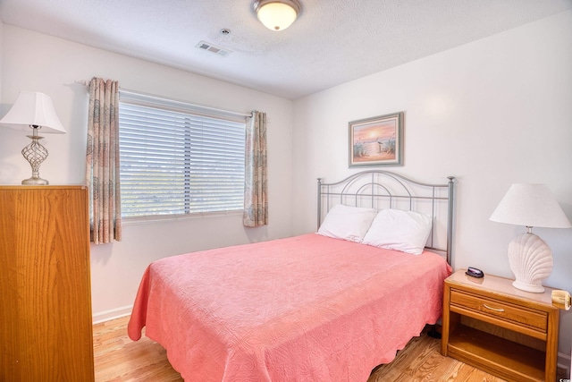 bedroom with light hardwood / wood-style floors and a textured ceiling