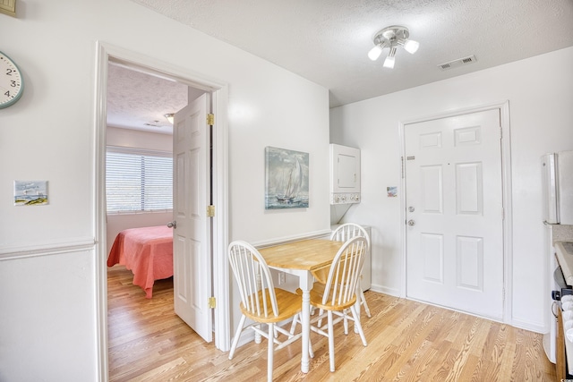 dining space with a textured ceiling and light wood-type flooring