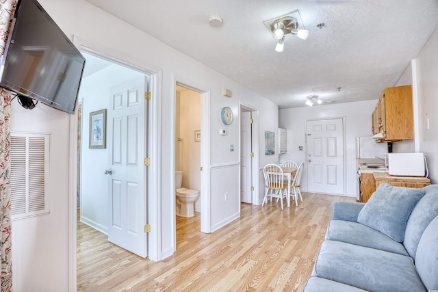 living room with a textured ceiling and light wood-type flooring