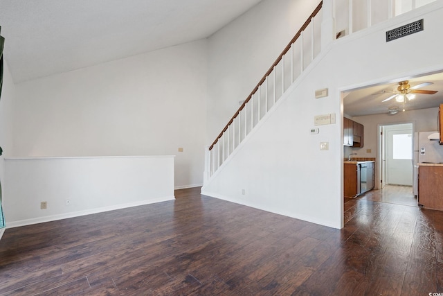 unfurnished living room with dark hardwood / wood-style floors, sink, ceiling fan, and a towering ceiling