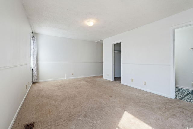 empty room with light colored carpet and a textured ceiling