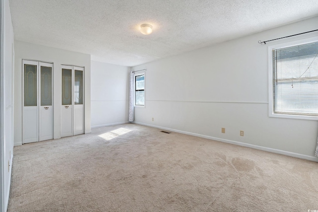 carpeted empty room featuring a textured ceiling