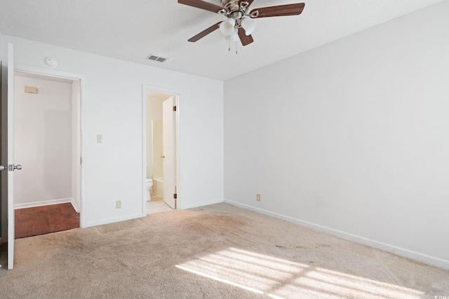 unfurnished bedroom featuring light carpet, connected bathroom, and ceiling fan