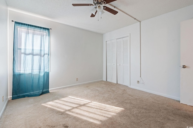 unfurnished bedroom with ceiling fan, light colored carpet, a textured ceiling, and a closet