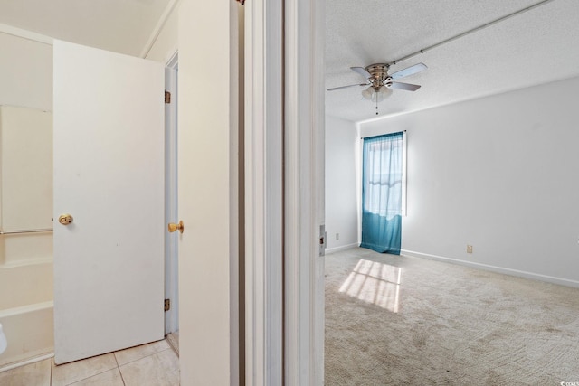 corridor featuring light colored carpet and a textured ceiling