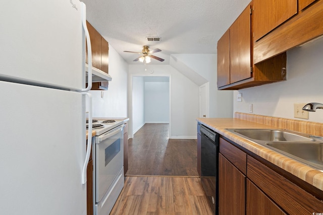 kitchen featuring sink, white appliances, ceiling fan, dark wood-type flooring, and a textured ceiling