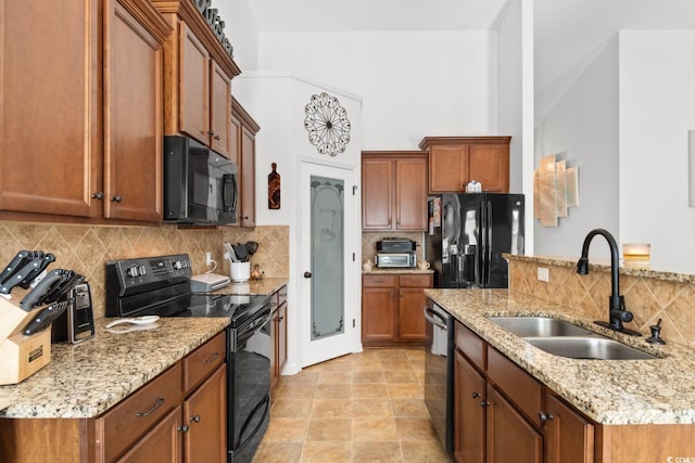 kitchen with sink, backsplash, light stone counters, and black appliances