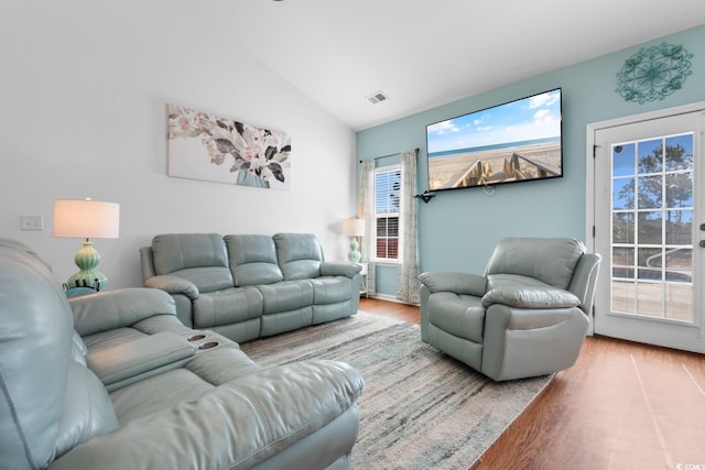 living room with lofted ceiling, a wealth of natural light, and light hardwood / wood-style floors