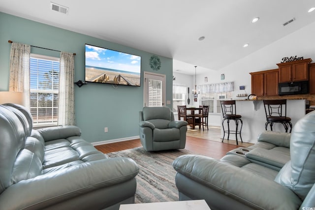 living room featuring vaulted ceiling and light hardwood / wood-style flooring