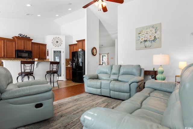 living room with ceiling fan, high vaulted ceiling, and light wood-type flooring