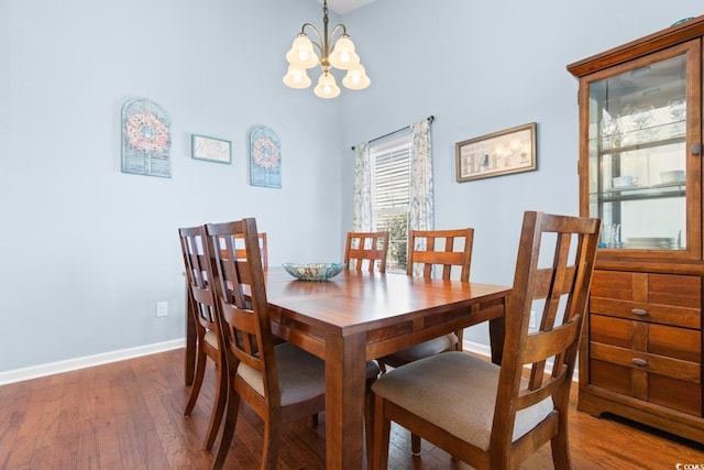 dining space with dark wood-type flooring and a notable chandelier