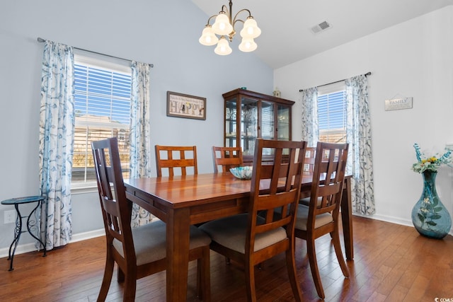 dining space featuring lofted ceiling, dark wood-type flooring, and a chandelier