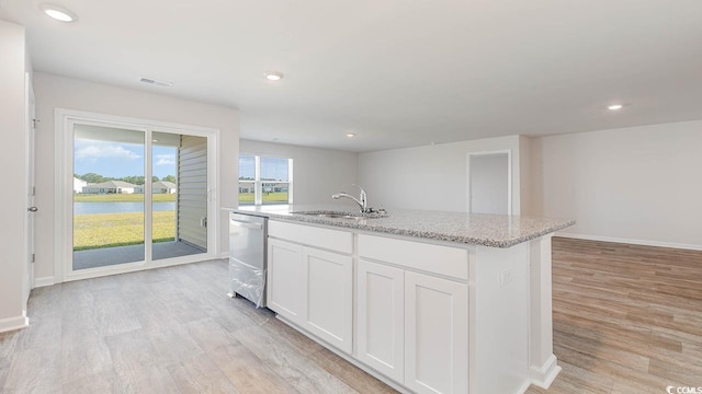 kitchen with a kitchen island with sink, light wood-style flooring, a sink, white cabinetry, and dishwasher