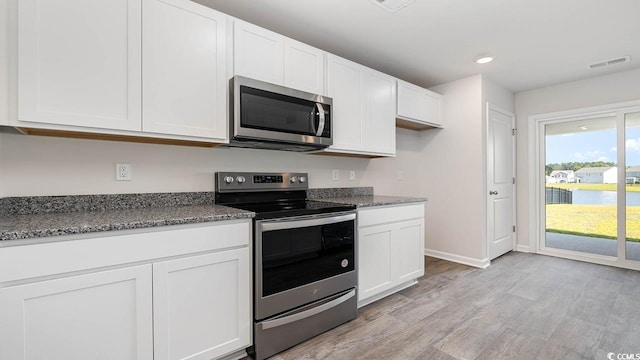 kitchen featuring appliances with stainless steel finishes, white cabinets, visible vents, and light wood-style floors