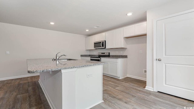 kitchen featuring appliances with stainless steel finishes, white cabinets, a sink, and wood finished floors