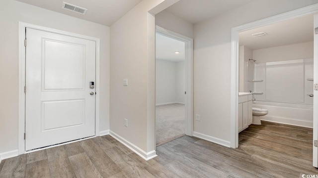 entryway with wood finished floors, visible vents, and baseboards