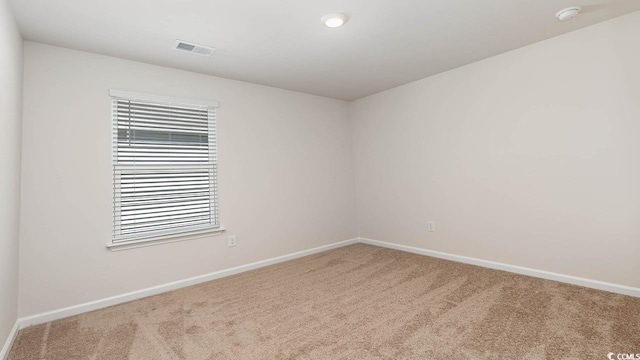 spare room with carpet floors, visible vents, and baseboards