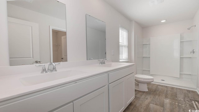 full bathroom featuring double vanity, wood finished floors, a sink, and toilet