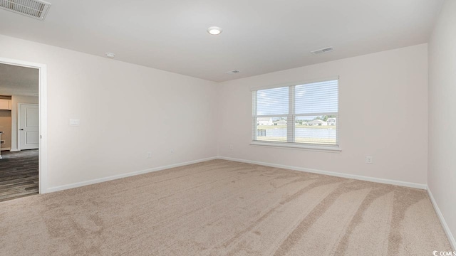 carpeted spare room with visible vents and baseboards