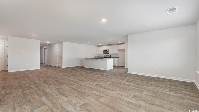 unfurnished living room featuring light wood-style flooring, recessed lighting, visible vents, and baseboards