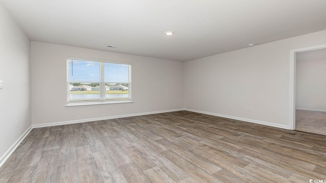 unfurnished room featuring visible vents, baseboards, and wood finished floors