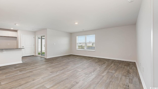 unfurnished living room featuring light wood-style floors, recessed lighting, and baseboards