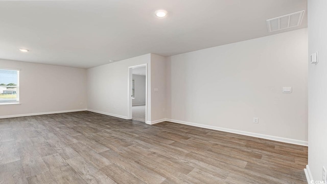 empty room with baseboards, visible vents, wood finished floors, and recessed lighting