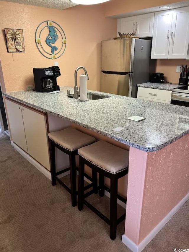9550 Shore Dr Unit 1721, Myrtle Beach, SC 29572 - kitchen featuring freestanding refrigerator, carpet floors, a sink, white cabinets, and a breakfast bar area